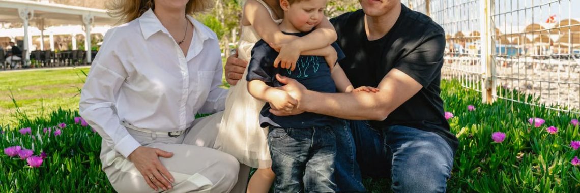 Family of four enjoying a sunny day outdoors in Kemer, smiling and spending quality time together.